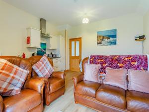 a living room with two leather couches and a kitchen at The Barn Mey in Scarfskerry