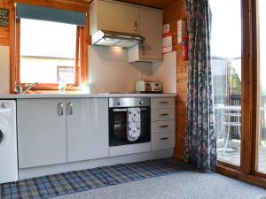 a kitchen with a stove top oven next to a window at Loch Arkaig in Banavie +5 photos