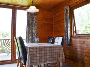 a dining room with a table and chairs and windows at Loch Arkaig in Banavie