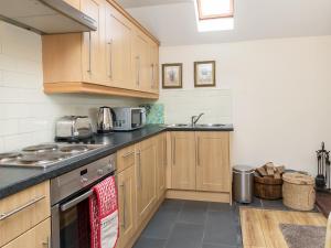 a kitchen with wooden cabinets and a stove top oven at Bonnie's Bothy in Port of Menteith