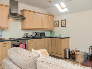 a kitchen with wooden cabinets and a couch at Bonnie's Bothy in Port of Menteith