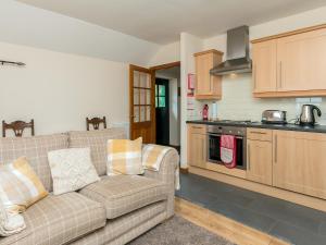 a living room with a couch and a kitchen at Bonnie's Bothy in Port of Menteith