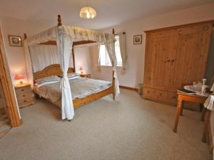 a bedroom with a canopy bed and a wooden cabinet at Humbleton Falls in Wooler