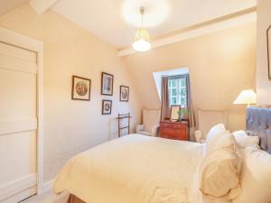 a bedroom with a white bed and a mirror at Rhoda's Cottage in Strachur