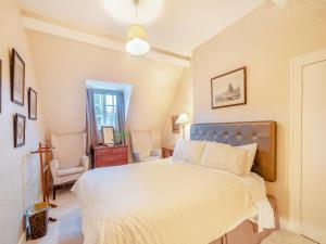 a bedroom with a large bed and a chair at Rhoda's Cottage in Strachur