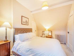 a bedroom with a large white bed and a lamp at Rhoda's Cottage in Strachur