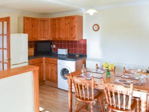 a kitchen with a table and a refrigerator and a washer and dryer at Ricann - Ukc4244 in Lanreath