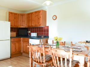 a kitchen with a wooden table and a white refrigerator at Ricann - Ukc4244 in Lanreath