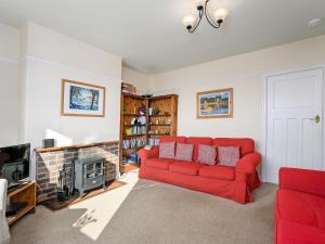 a living room with a red couch and a fireplace at Cartref in Llysfaen