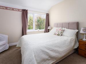 a bedroom with a white bed and a window at Cartref in Llysfaen