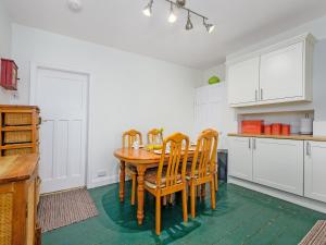 a kitchen with a wooden table and chairs at Cartref in Llysfaen