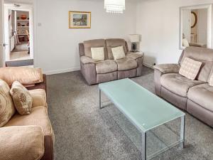 a living room with couches and a coffee table at Ivydene Cottage in Cromarty