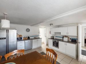 a kitchen with white cabinets and a table and chairs at Ivydene Cottage in Cromarty