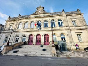 a large building with red doors and a clock tower at Le Nid Laonnois Apartment in Laon