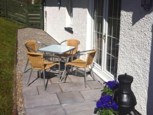 a patio with a table and chairs next to a window at Glenfruin Lodge in Helensburgh +1 photo