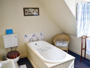 a bathroom with a sink and a toilet and a tub at Reid's Cottage in Lairg