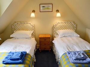 two beds in a attic room with two towels on them at Reid's Cottage in Lairg