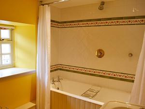 a bathroom with a tub and a shower and a sink at Reid's Cottage in Lairg