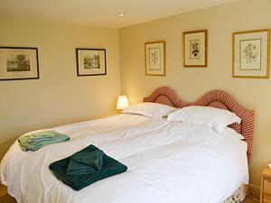 a bedroom with a white bed with a green bow on it at Reid's Cottage in Lairg