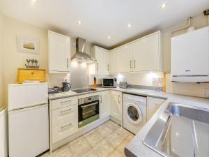 a kitchen with white cabinets and a washer and dryer at Tweed Cottage in Alnwick