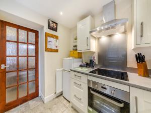 a kitchen with white cabinets and a stove top oven at Tweed Cottage in Alnwick +11 photos