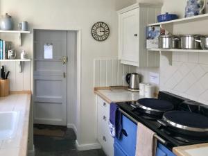a kitchen with white cabinets and a stove top oven at Sea Star Cottage in Fowey