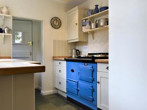 a kitchen with blue cabinets and a blue island at Sea Star Cottage in Fowey