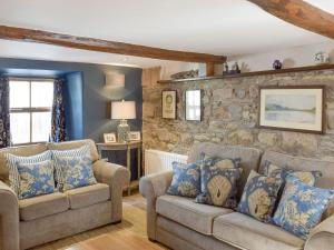a living room with two couches and a stone wall at Windy Nook in Pooley Bridge