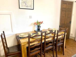 a dining room table and chairs with a table and a vase of flowers at Jemima's Cottage in Bassenthwaite