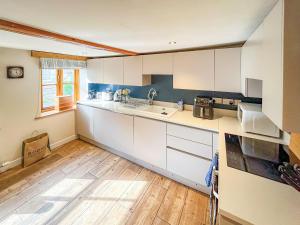 a kitchen with white cabinets and a wooden floor at Windy Nook in Pooley Bridge +12 photos
