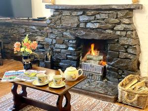 a stone fireplace with a table with cups at Jemima's Cottage in Bassenthwaite