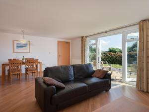 a living room with a leather couch and a dining room at 2 Red Rock Apartments in Dawlish Warren