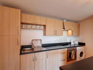 a kitchen with wooden cabinets and a sink and a dishwasher at 2 Red Rock Apartments in Dawlish Warren