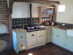 a kitchen with white cabinets and a stove at Spring Farm Barn in Grindale
