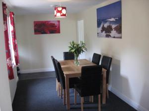 a dining room with a wooden table and black chairs at Springer Cottage in Llanstephan