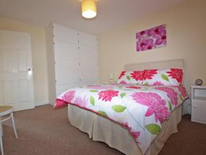 a bedroom with a bed with a pink and white comforter at Springer Cottage in Llanstephan +17 photos