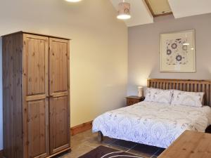 a bedroom with a bed and a wooden cabinet at Padgett Lodge - 23052 in Folkton