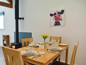 a dining room table with a cow painting on the wall at The Dairy Uk13198 in Butterwick