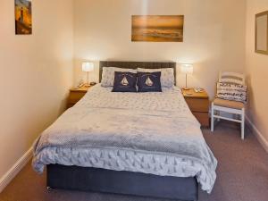 a bedroom with a large bed with two tables and a chair at Harbour Retreat in Garlieston +19 photos