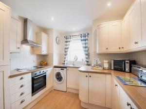a kitchen with white cabinets and a washer and dryer at Harbour Retreat in Garlieston