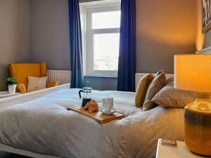 a bedroom with a bed with a tray of food on it at Bertram Cottage in Swarland