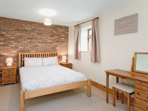 a bedroom with a bed and a brick wall at Close Cottage - W41944 in Filey