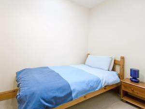 a bedroom with a bed with blue sheets and a nightstand at Close Cottage - W41944 in Filey