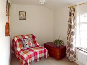 a bedroom with a chair and a table and a window at Brock Cottage in Broughton in Furness