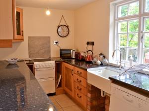 a kitchen with a sink and a clock on the wall at Brock Cottage in Broughton in Furness
