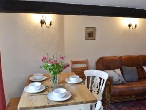 a table with a vase of flowers and a couch at Brock Cottage in Broughton in Furness