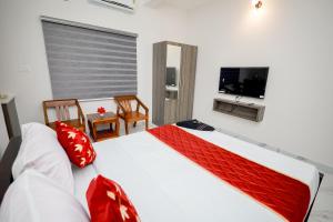 a bedroom with a bed with red pillows and a television at Royal La Casa in Cochin