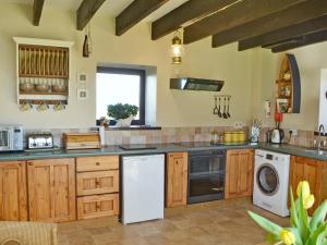 a kitchen with wooden cabinets and a white dishwasher at Sandsedge Cottage in Ellington