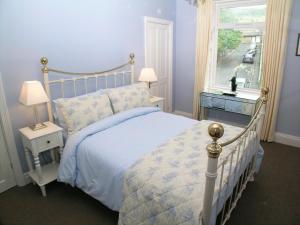 a bedroom with a bed with blue walls and a window at Ted's House in Mytholmroyd