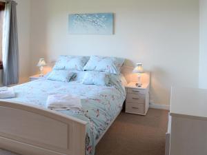 a bedroom with a bed with blue sheets and two lamps at Deo Na Mara in Midtown Brae